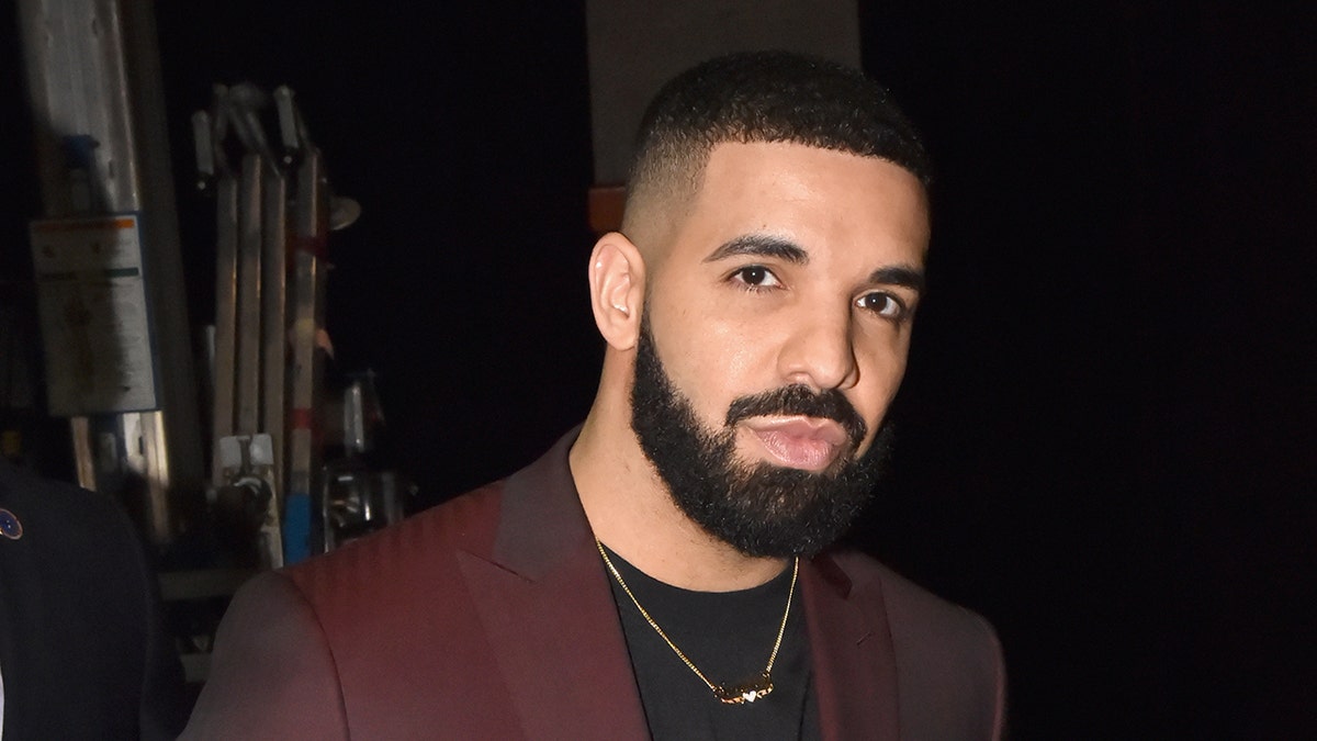 O rapper Drake usa um terno vermelho em uma premiação.