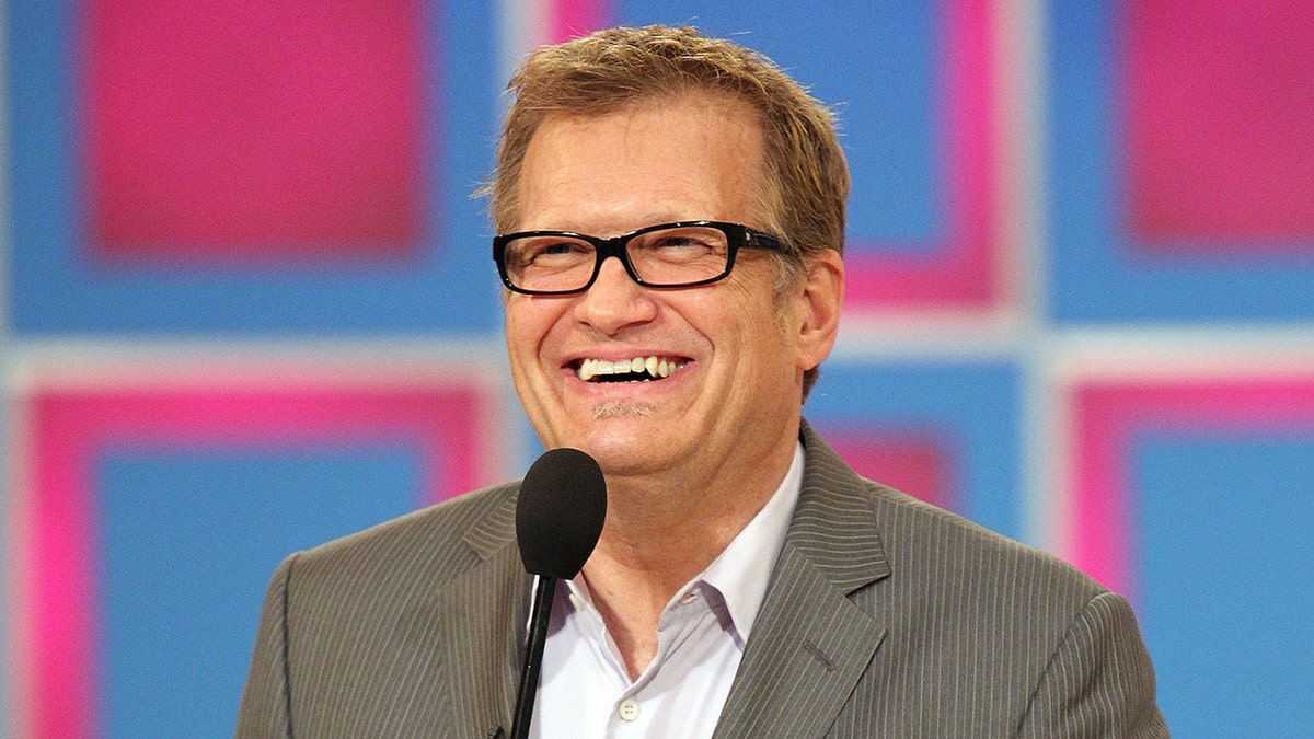Drew Carey holds microphone during The Price is Right hosting gig.