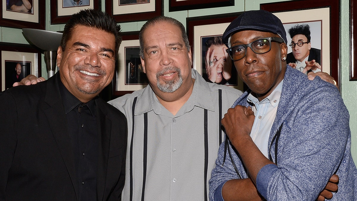George Lopez in black smiles with Rudy Moreno in a grey shirt with black lines and Arsenio Hall in a blue shirt