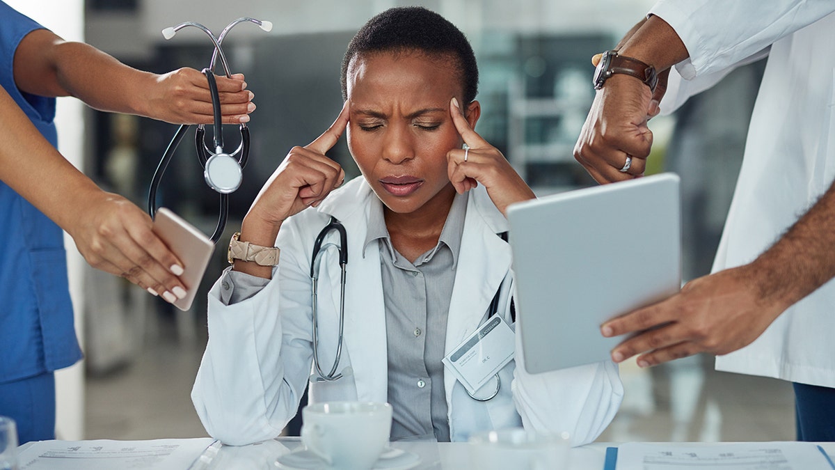stressed doctor surrounded by tools and technology