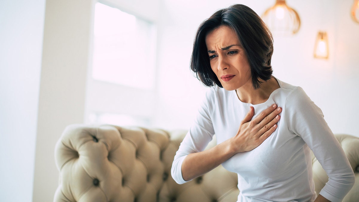 woman holds her heart in pain