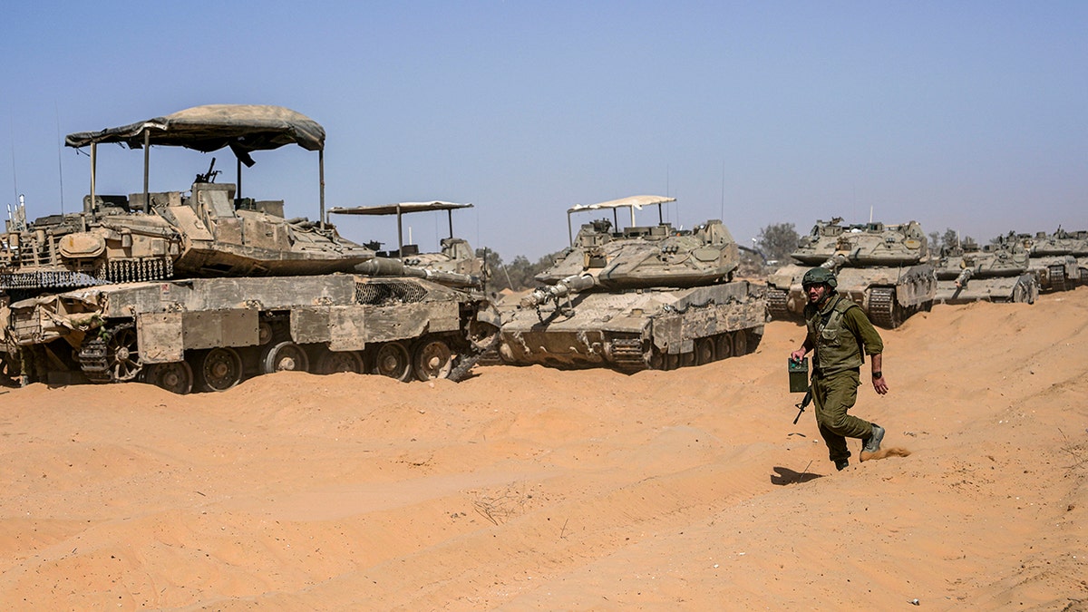 Israeli worker stepping past tank