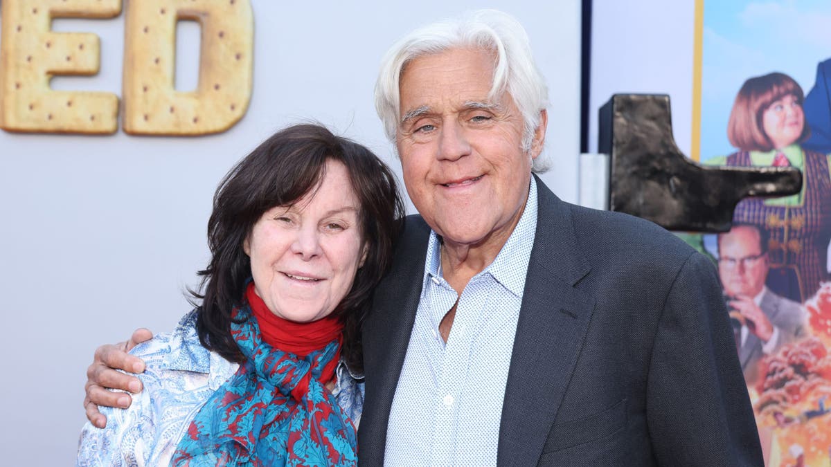 Jay Leno and woman Mavis Leno grin while attending "unfrosted" premiere.