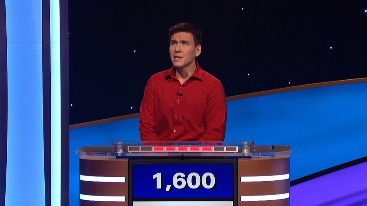 James Holzhauer in a red shirt looks up as he answers a question on "Jeopardy! Masters"