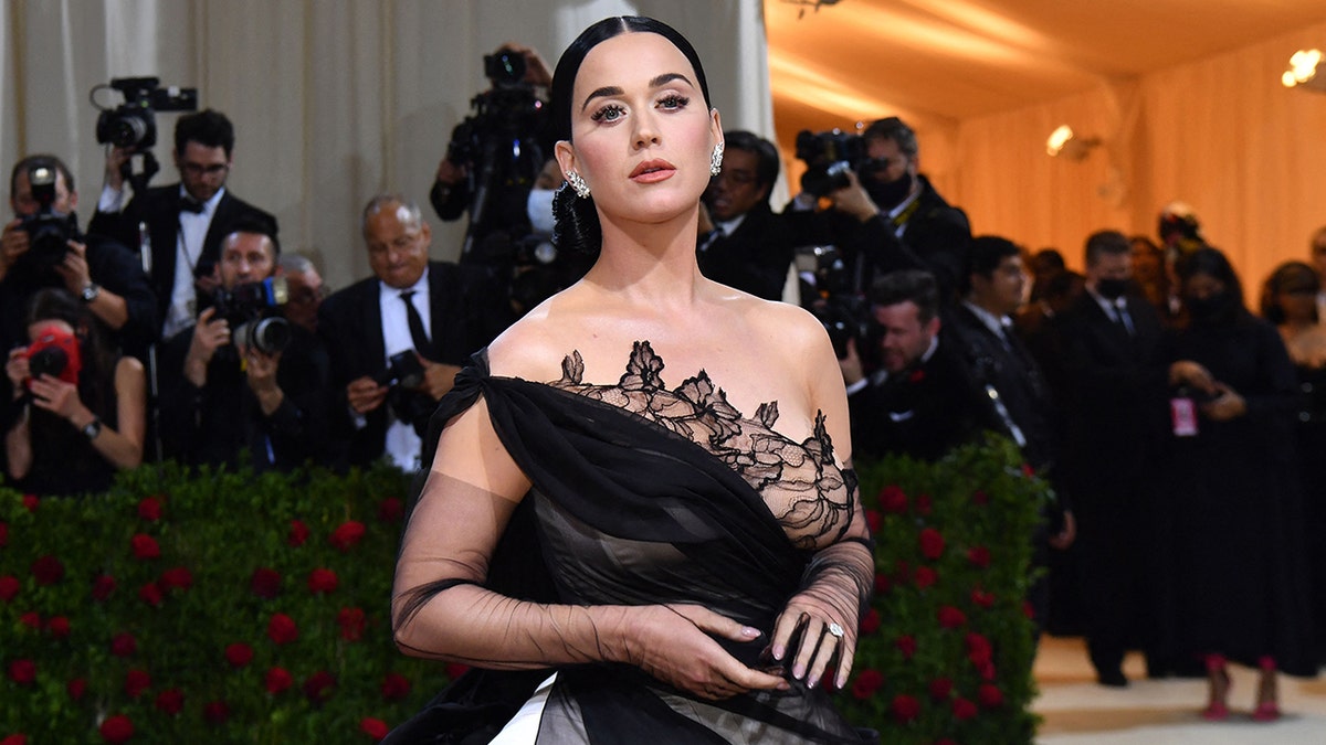 Katy Perry in a one shoulder black dress with lace detail looks longingly at the camera at the Met Gala in 2022
