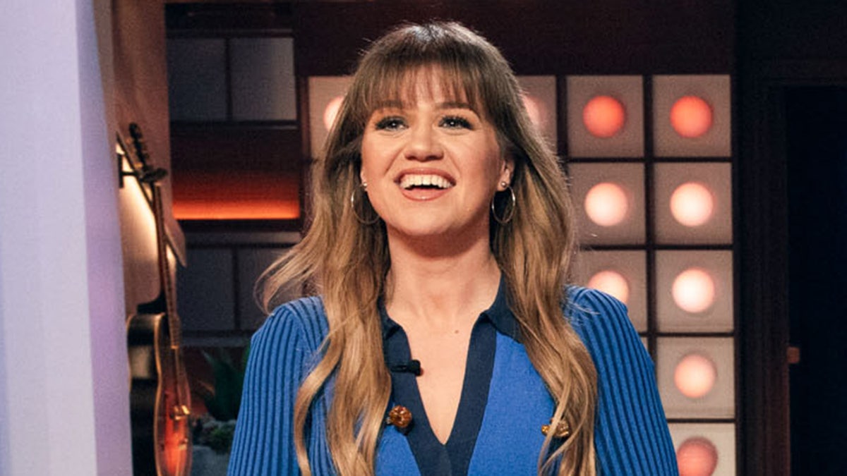 Kelly Clarkson in a blue sweater smiles on "The Kelly Clarkson Show"