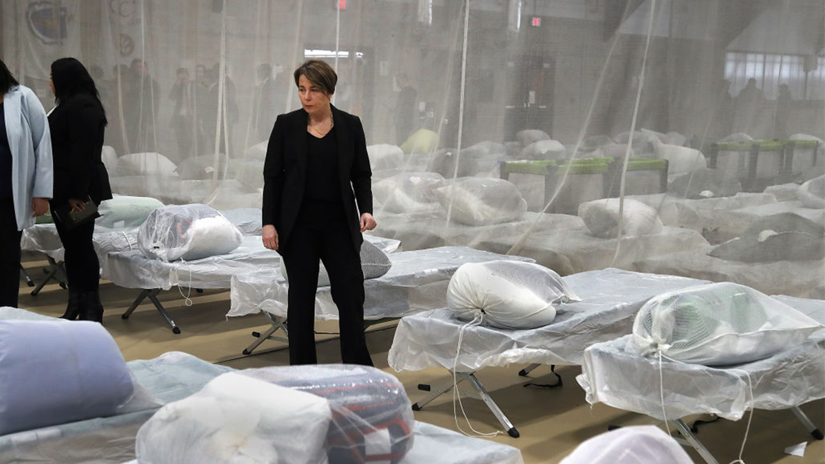 Massachusetts Governor Maura Healey pauses to look at the Army cots set up on the gym floor as State and local officials toured the Melnea A. Cass Recreational Complex.