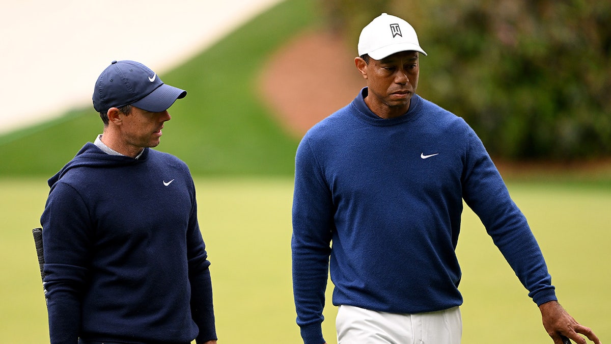 Rory McIlroy walks the green with Tiger Woods