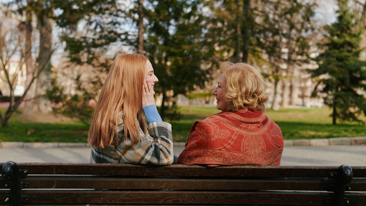 mother talking to daughter on bench sharing advice