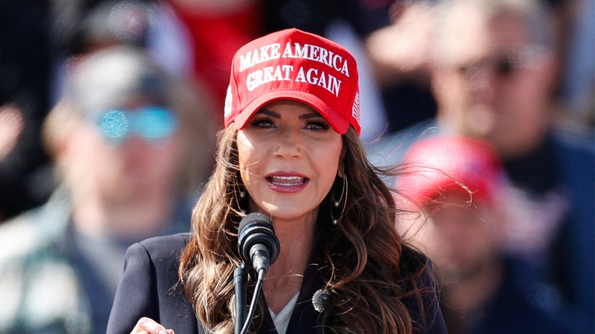 Kristi Noem wearing a reddish  Make America Great Again hat