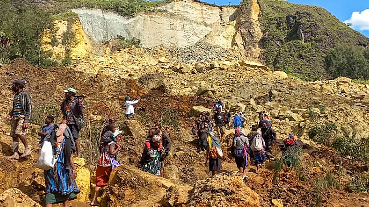 people walk over landslide debris