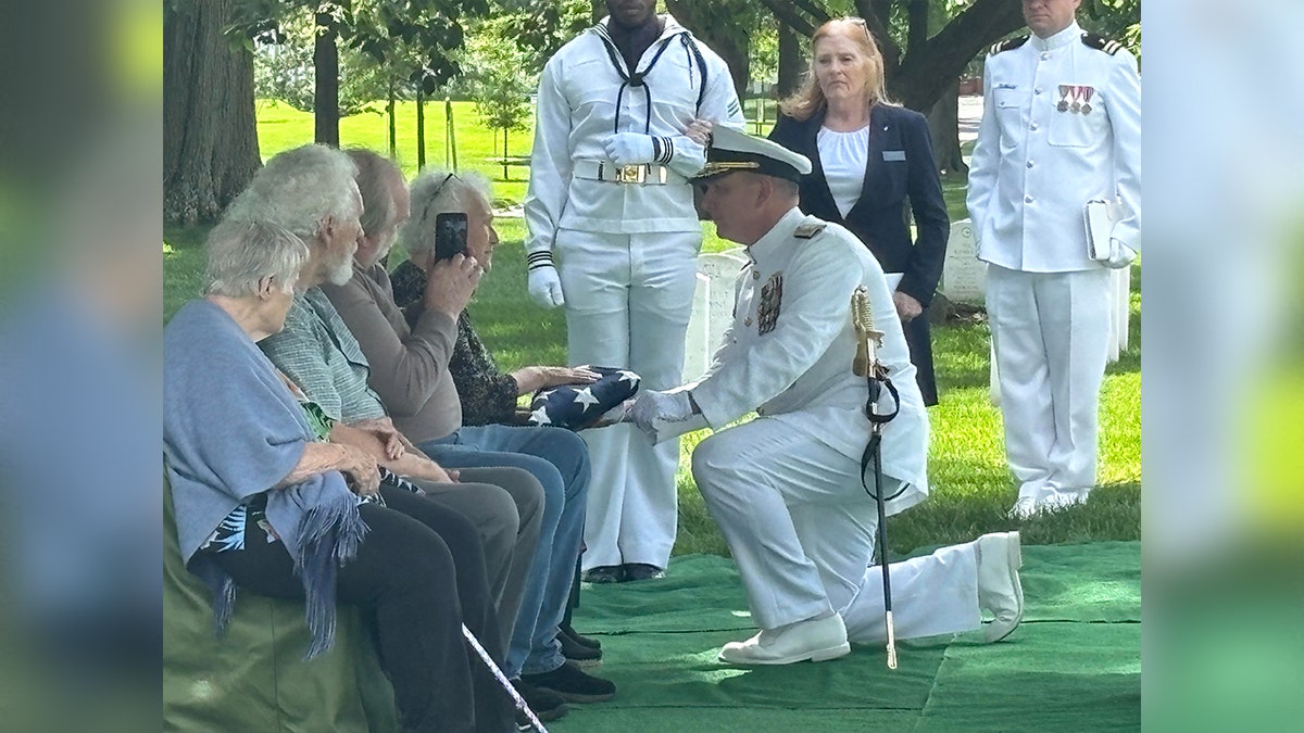 admiral hands flag to woman during funeral