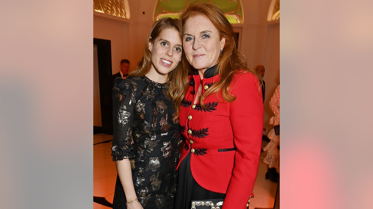 Princess Beatrice in a black top leans into mother Sarah Ferguson in a red jacket
