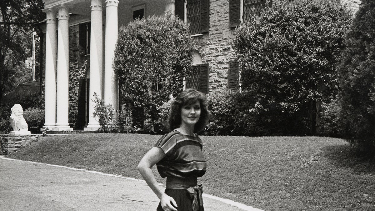 Priscilla Presley standing outside Graceland.