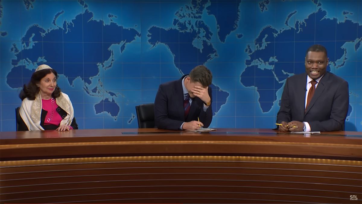 Wide shot of Colin Jost and Michael Che during the season finale of "Saturday Night Live" 'Weekend Update' segment with a woman portraying Rabbi Jill