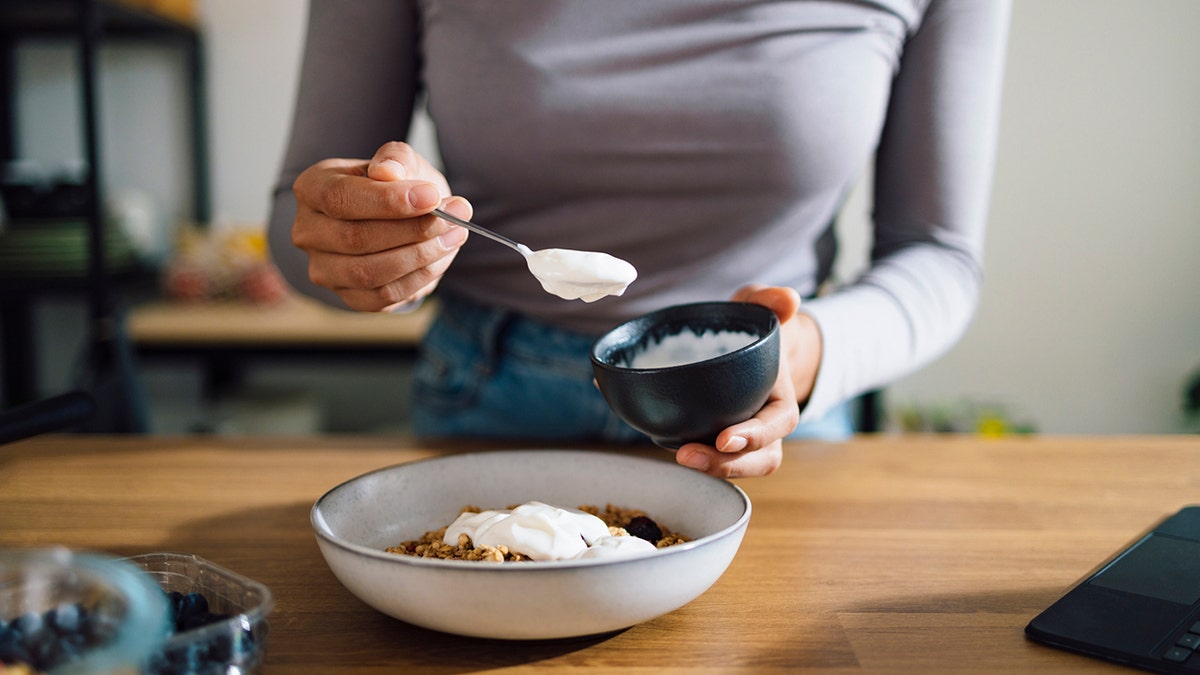 woman preparing bowl of yogurt
