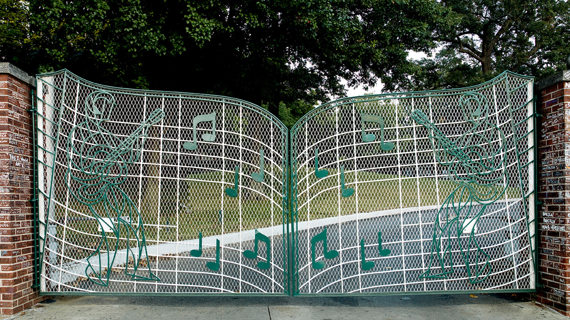 A green gate with music notes guards the driveway leading to Graceland.