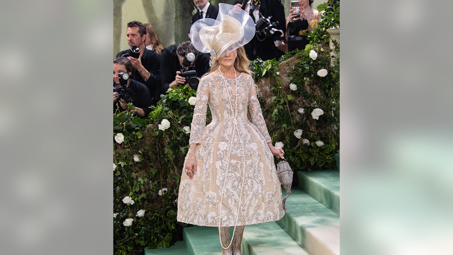 Sarah Jessica Parker at the Met Gala 2024 red carpet wearing a Richard Quinn corset gown and large hat.