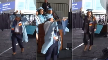 Columbia University student in handcuffs rips up diploma on commencement stage in act of protest