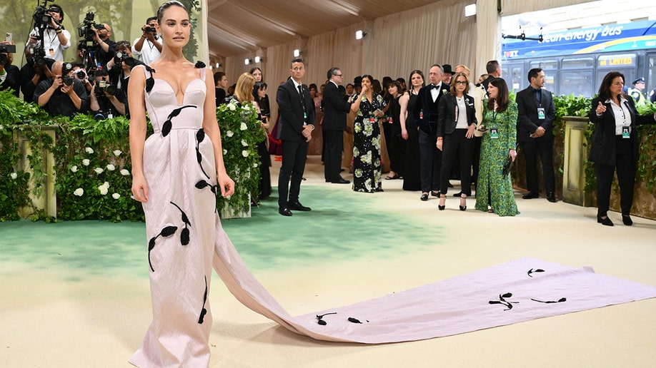 2024 Met Gala attendee Lily James wears pink dress with draping train.