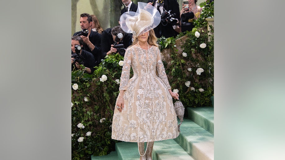 Sarah Jessica Parker at the Met Gala 2024 red carpet wearing a Richard Quinn corset gown and large hat.