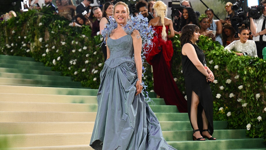 Uma Thurman at the Met Gala 2024 red carpet in a blue Tori Burch gown with butterflies on the shoulders.