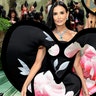 Demi Moore at the Met Gala 2024 red carpet, wearing a black dress with floral print designed by Harris Reed.