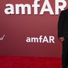 Cher walked the red carpet at the amfAR Gala alongside Alexander Edwards in a black dress with sheer paneling and a black coat, while he wore a black suit.