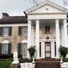 The front of the brown stone home features a black ceiling, white beams, lion statues and two benches at the base of the stairs.