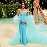 Lea Michele cradles her baby bump wearing a teal gown on the Met Gala red carpet.