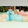 Lea Michele cradles her baby bump wearing a teal gown on the Met Gala red carpet.