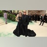 Meg Ryan at the Met Gala 2024 red carpet in a black Michael Kors dress walking with the designer