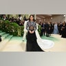 Riley Keough at the Met Gala 2024 red carpet in a dress with a bedazzled top, bare midriff and black flowy skirt.