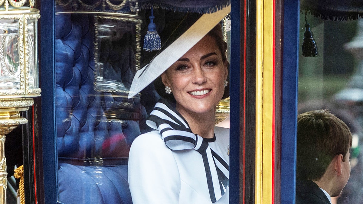 Un primer plano de Kate Middleton con un vestido blanco a rayas dentro de un carruaje en Trooping the Colour