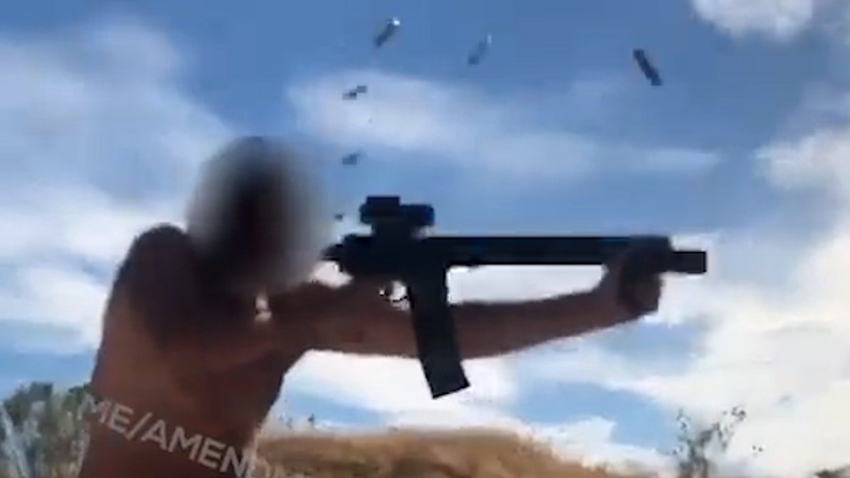 A still image taken from video shows a man firing what appears to be a fully automatic weapon