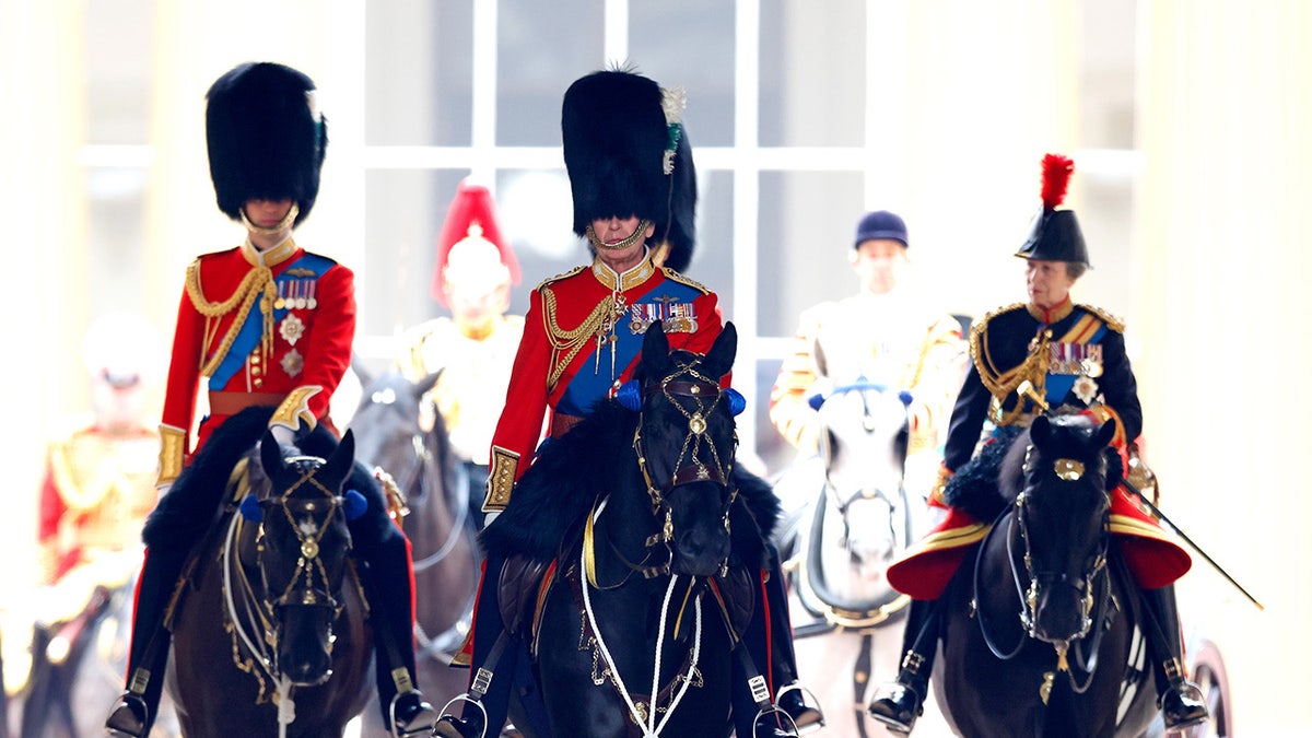 King Charles riding on horseback in between Prince William and Princess Anne