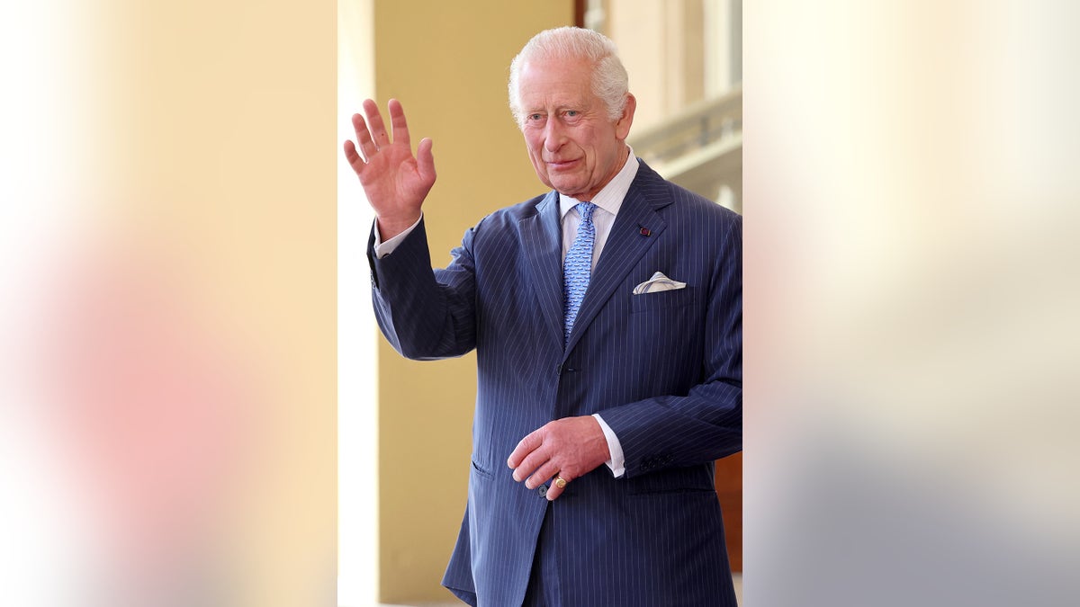 King Charles in a blue suit waving.