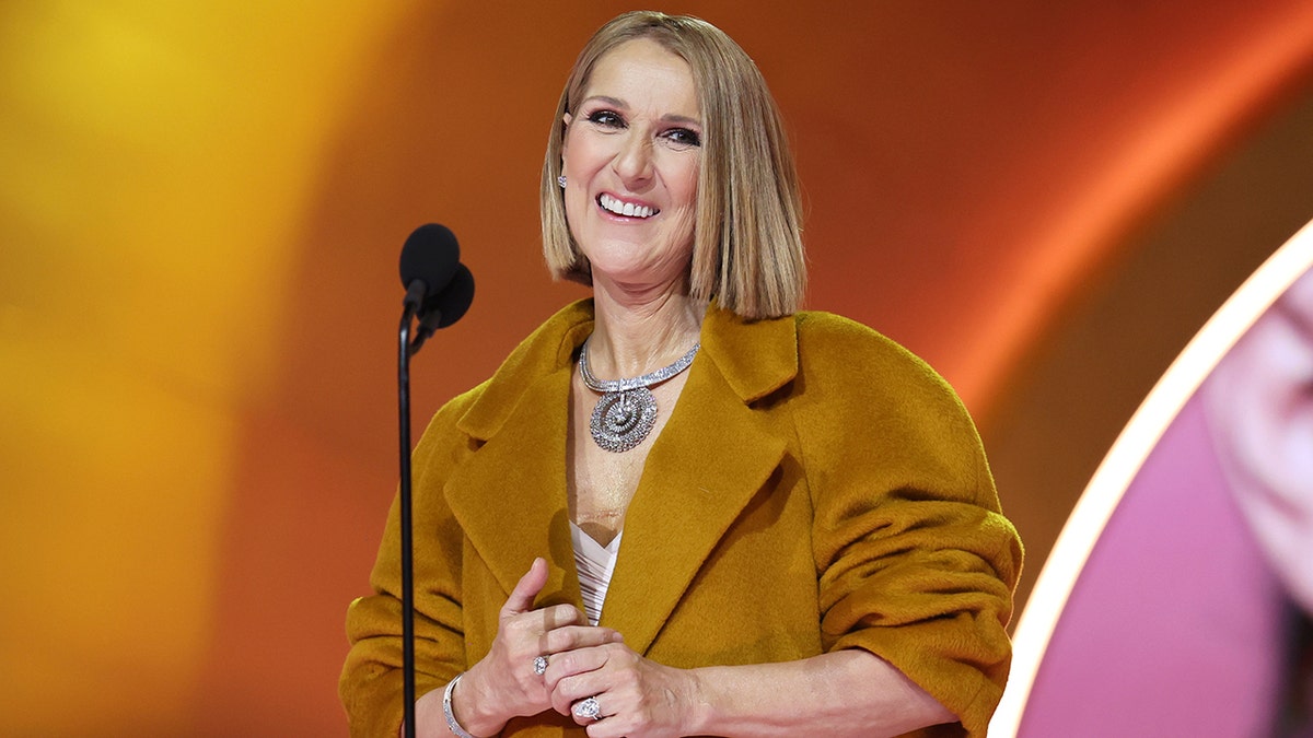 Celine Dion con una chaqueta naranja quemado en el escenario de los Premios Grammy