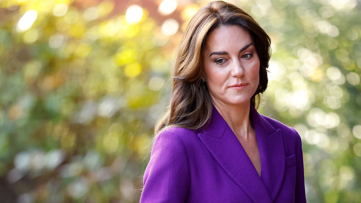 Kate Middleton looking concerned in a purple suit