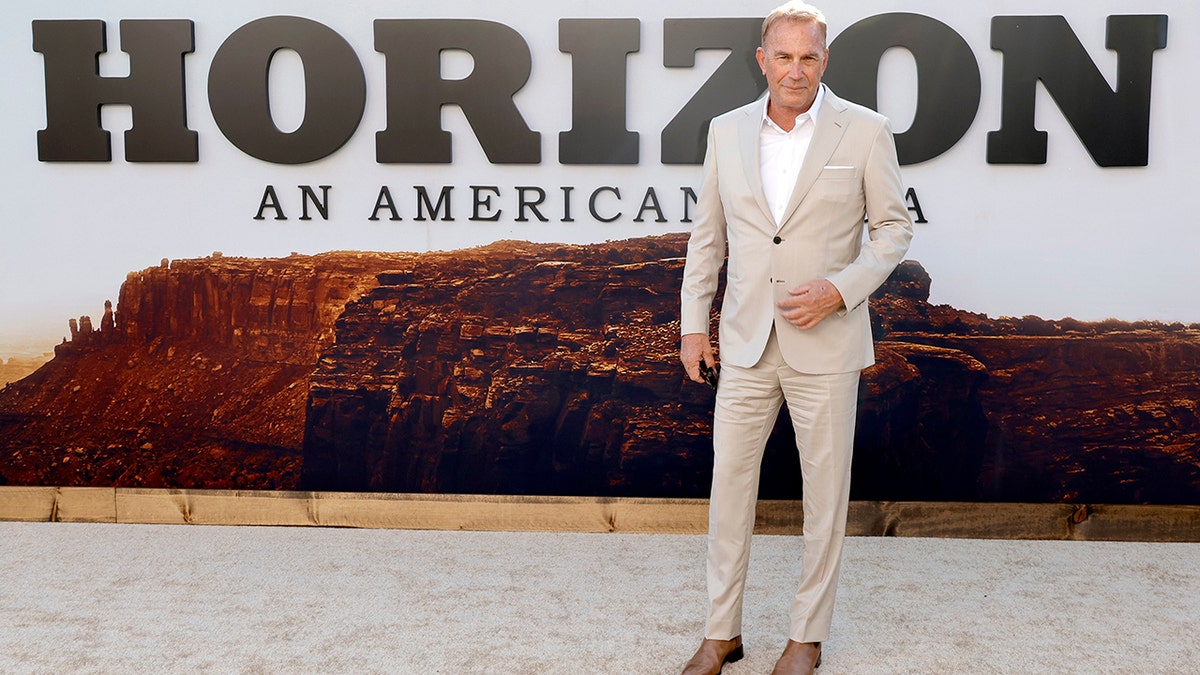 Kevin Costner usava um terno bege e mocassins marrons enquanto posava para fotos na estreia de "Horizon: Uma Saga Americana - Capítulo 1."