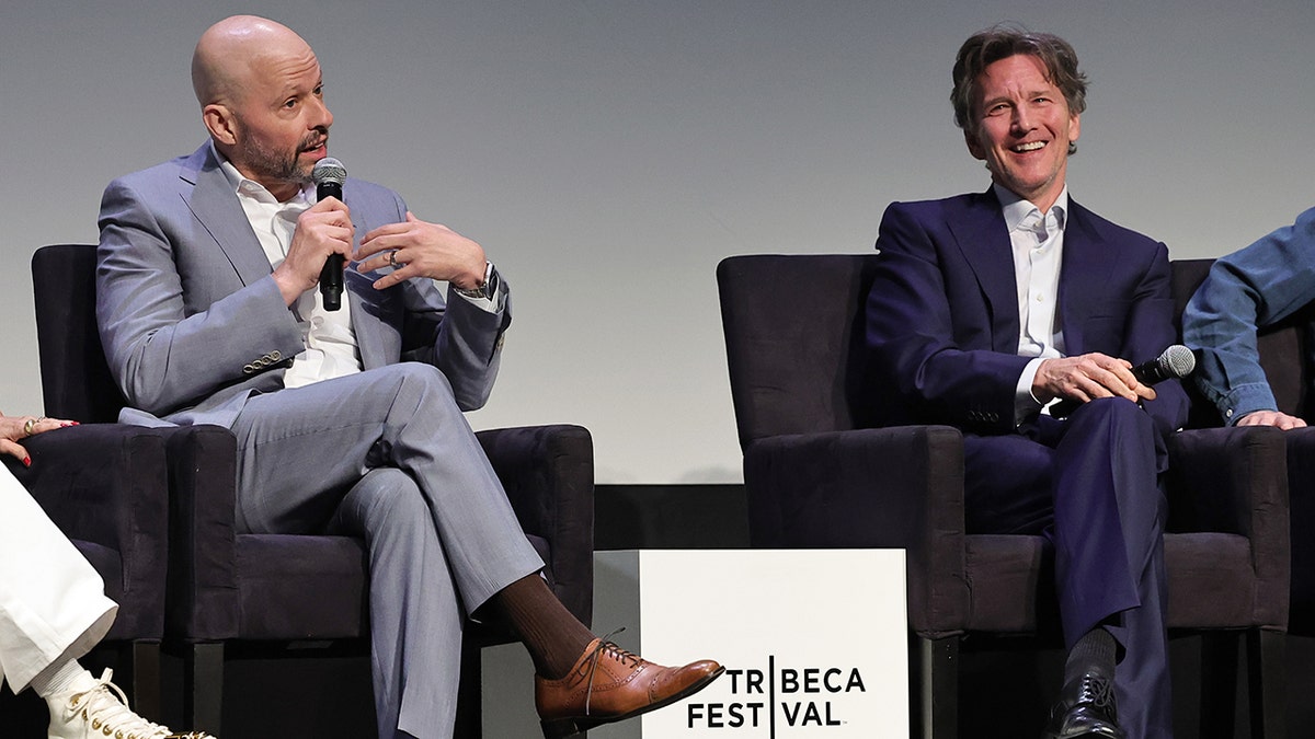 Jon Cryer in a light gray suit on stage with Andrew McCarthy at the Tribeca Film Fesitval