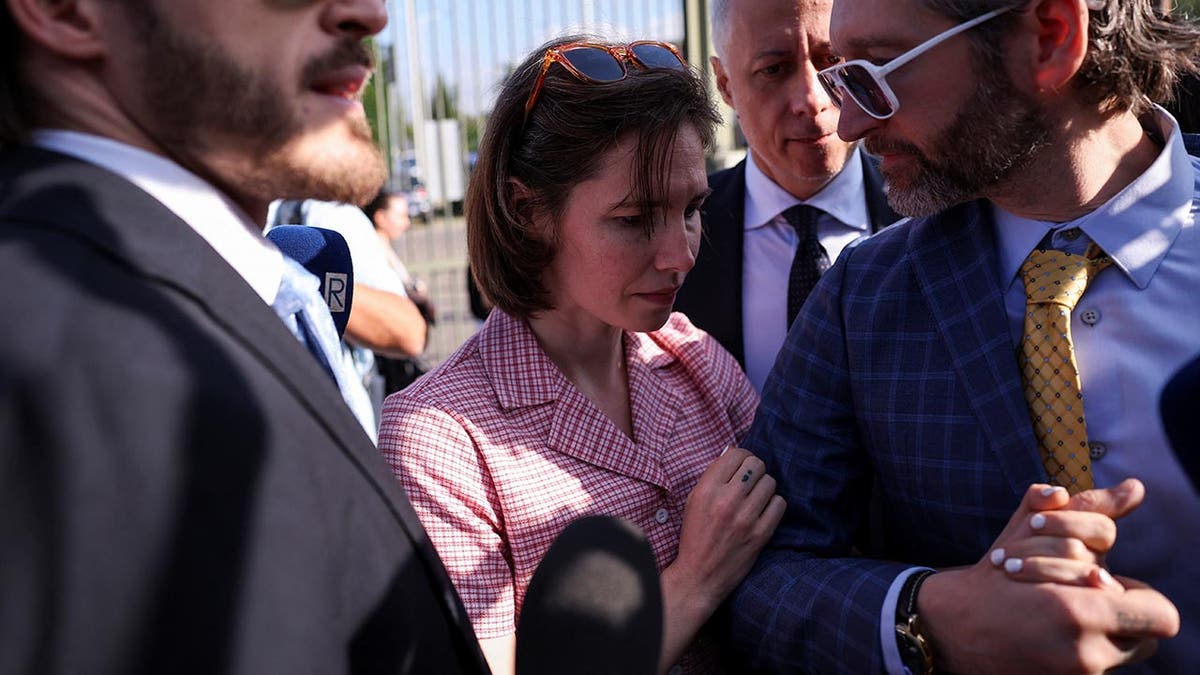Amanda Knox in a checkered shirt is emotional as she arrives at court flanked by her two male lawyers