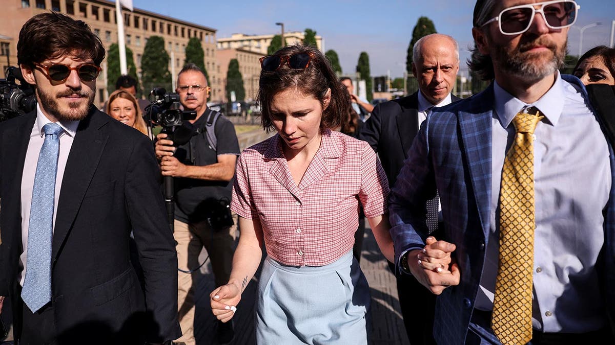 Amanda Knox in a checkered shirt is emotional as she arrives at court flanked by her two male lawyers