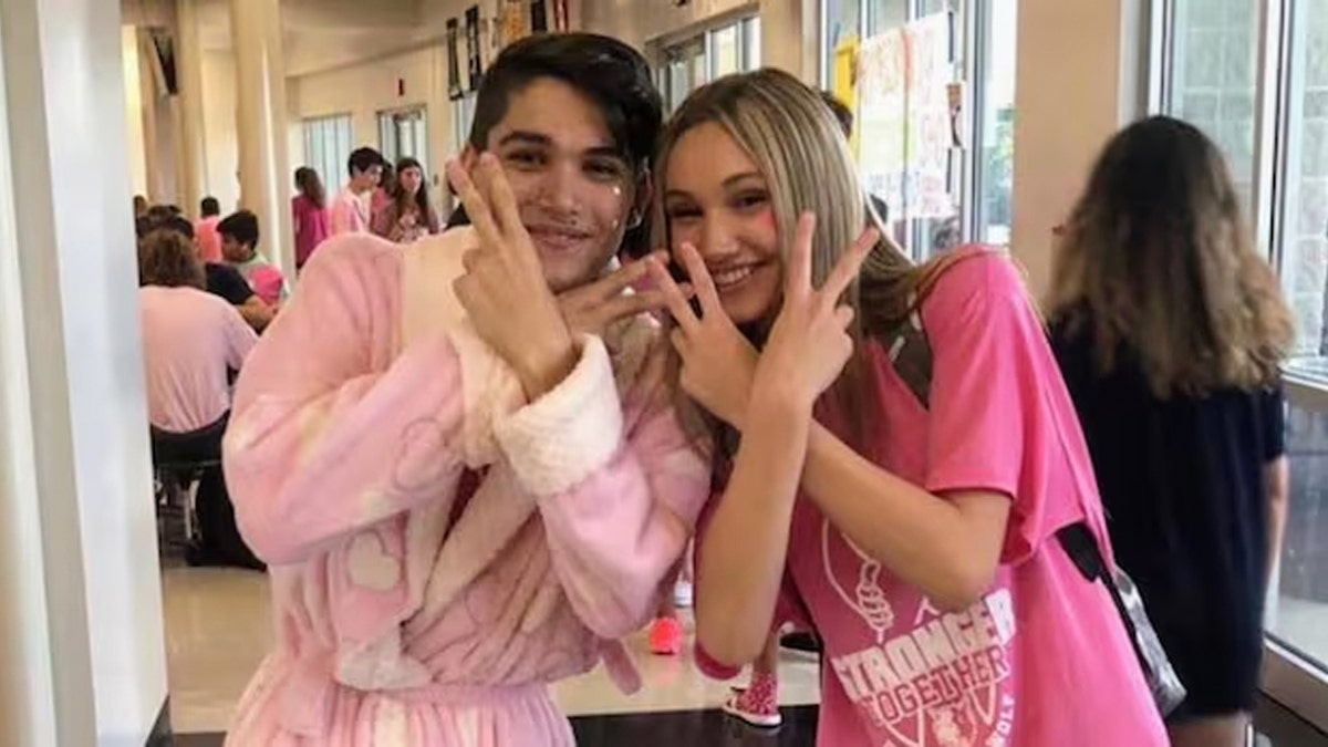 Bradley and Ava Hulett make "peace" signs and smile while wearing pink