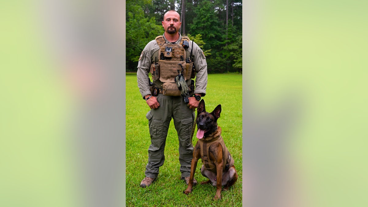 K9 agent and handler pose for portrait on a grassy clearing