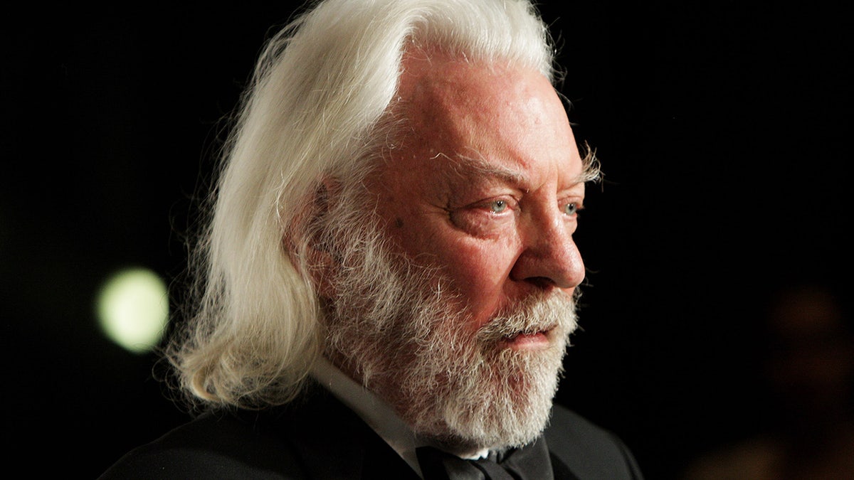 Donald Sutherland poses in the press room wearing black suit.