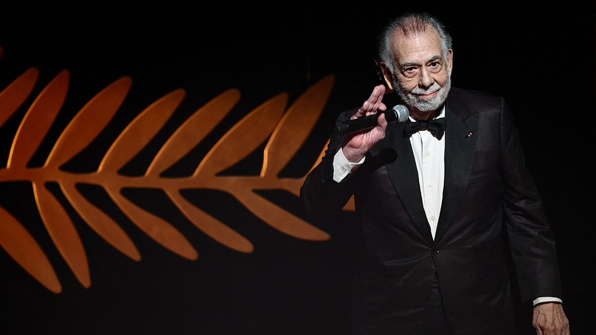 Francis Ford Coppola standing on stage and waving to audience
