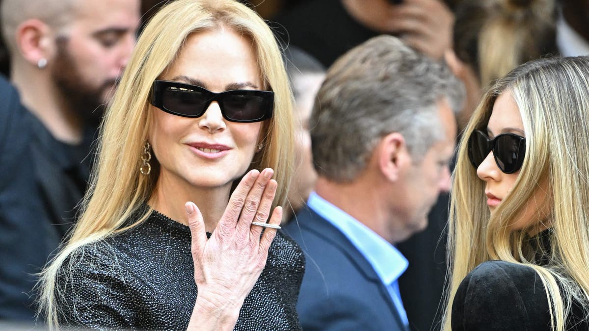 nicole kidman with her hand raised next to sunday rose