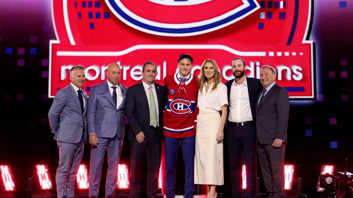 Celine Dion posing with Ivan Demidov, NHL officials and her son on stage