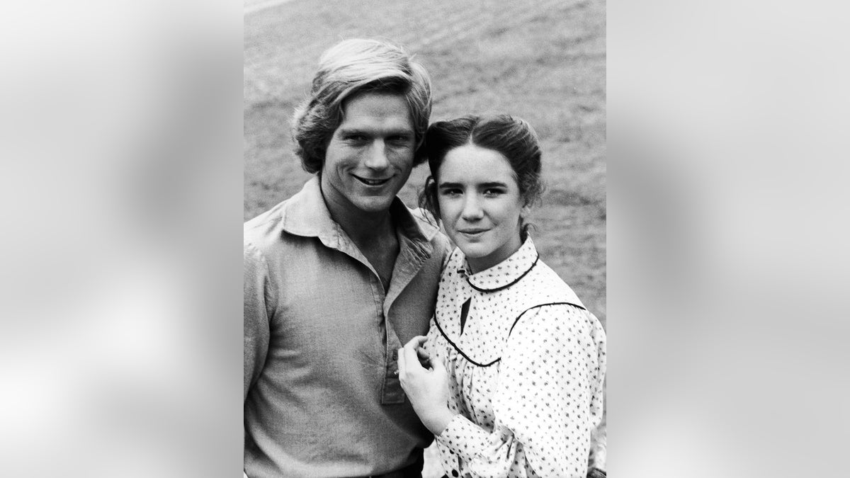 Dean Butler smiling next to Melissa Gilbert in a white and black polka dot dress.